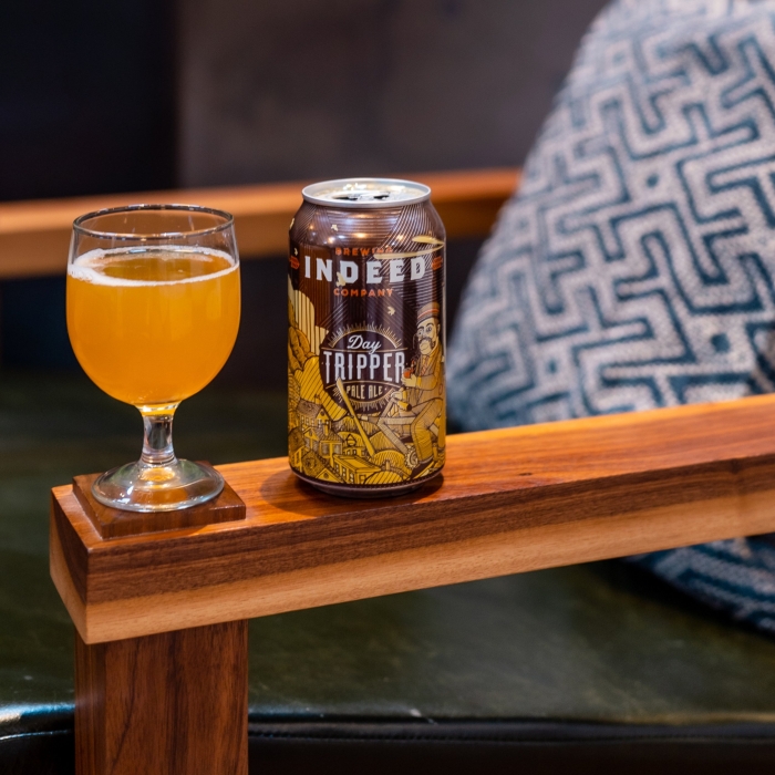 A glass of beer on the arm of a wooden chair